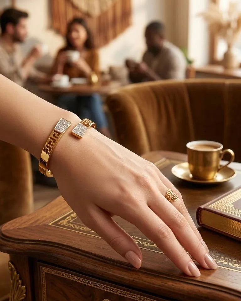 Hand with gold bracelet and ring on a wooden table in a cozy cafe setting